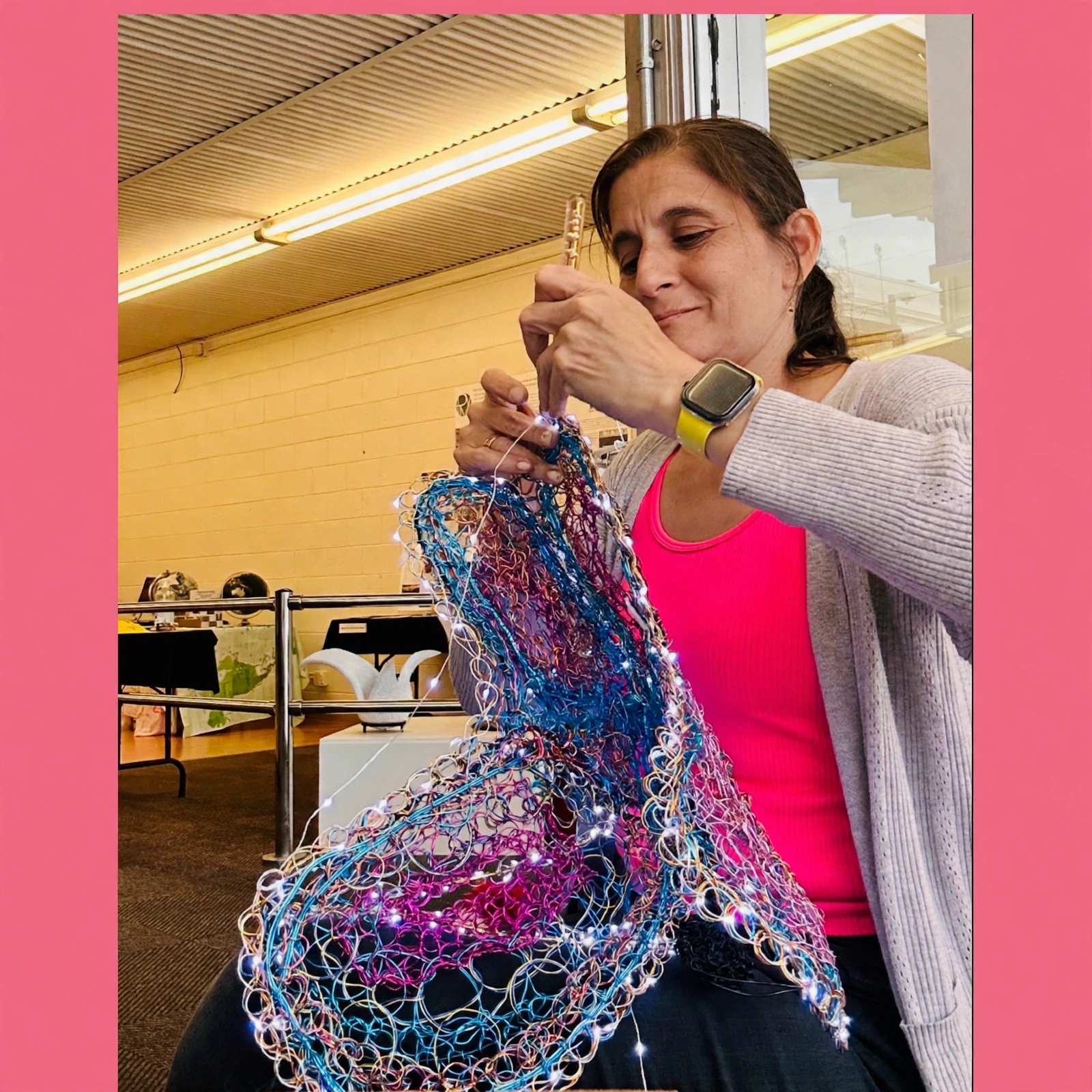 Marita Valdizan smiling while hand-crafting an illuminated wire sculpture